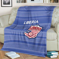 Blue football blanket with Liberia crest and wordmark, striped pattern on sofa