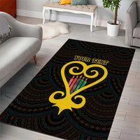 Black area rug with teal ornamental pattern and large yellow heart-shaped Sankofa symbol