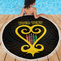 Round black beach blanket with white fringe, yellow heart and Adinkra pattern, 'Your Text' in use