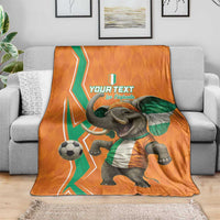 Orange football blanket draped on sofa, elephant in green scarf and soccer ball graphic