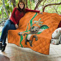 Orange custom quilt draped over sofa with elephant mascot and soccer ball pattern