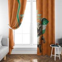 Orange curtains with elephant-and-flag artwork hanging by a white-framed window