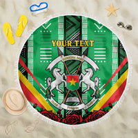 Round green beach blanket with Burkina Faso coat of arms graphic and white fringe edging
