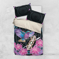 Purple and black bedding set laid flat with two round-pattern pillows and pink orchid print