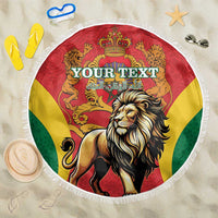 Round beach blanket with lion and crown graphic in red, yellow, and green with white fringe