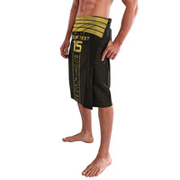 Black patterned lavalava skirt with green waistband and gold vertical text graphic, angled