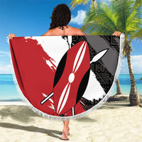 Round fringe beach blanket held on sand in black, white, red surfboard print
