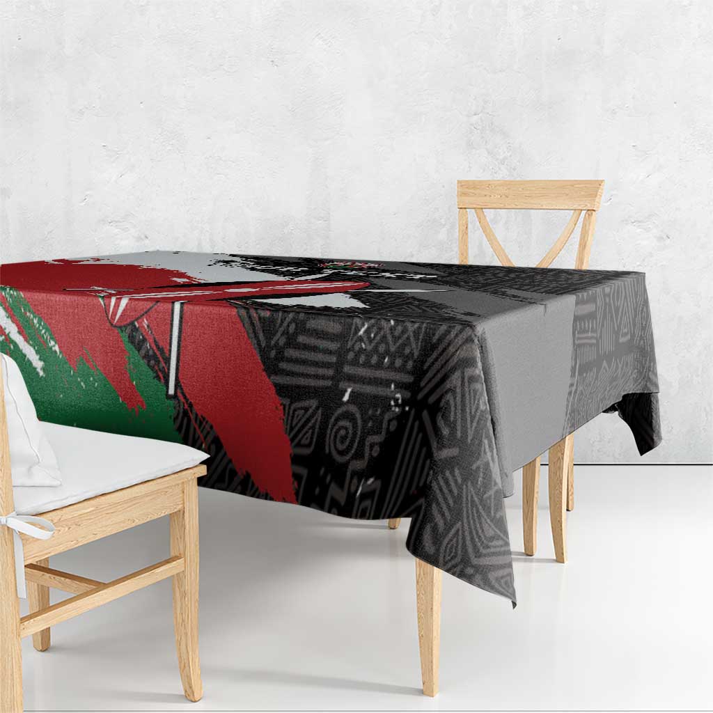 Black tablecloth with African design, red panel and green accent, hanging over table edge