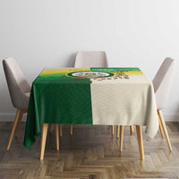 Square dining table covered with green and cream Nairobi tablecloth with round emblem