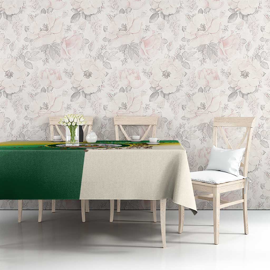 Green and cream Nairobi tablecloth on dining table with circular emblem against floral wall