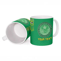 Green ceramic mug with Islamic emblem, gold “YOUR TEXT,” and ornate border design