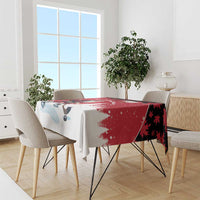 Red and white tablecloth draped over dining table with Santa hockey player motif