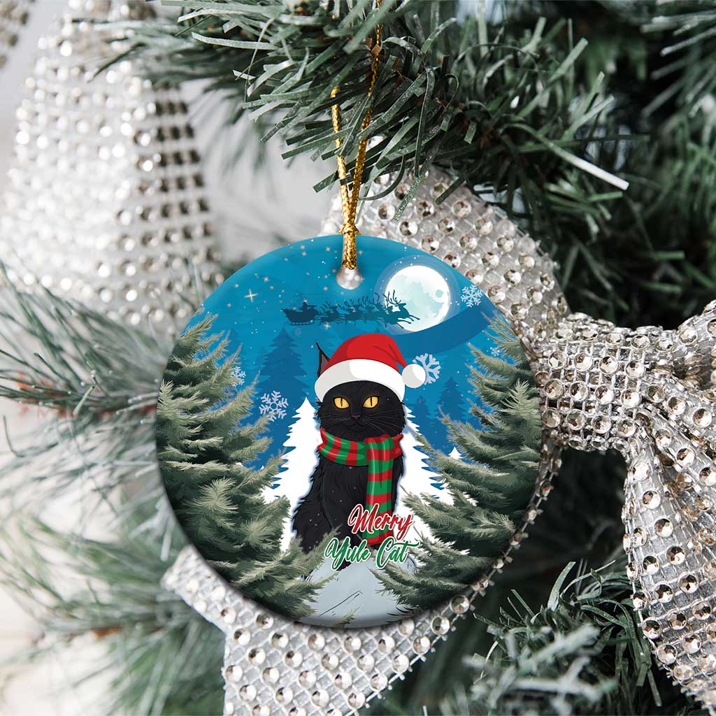 Blue round ceramic ornament on tree branches, with black cat in Santa hat and plaid scarf