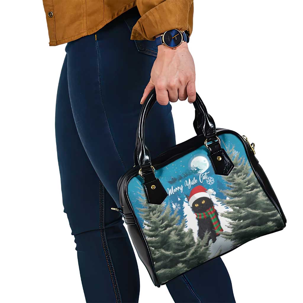 Blue shoulder handbag with black straps and Merry Yule cat print, side view.
