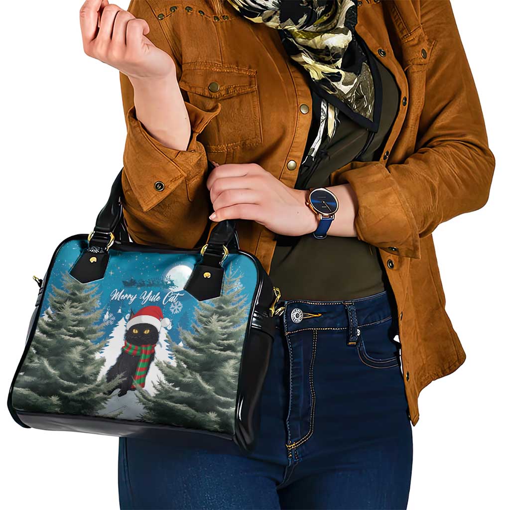 Blue handbag with black handles and Merry Yule cat trees graphic, held by model.