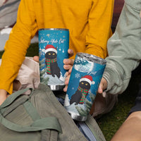 Two blue tumbler cups with black cat holiday graphics and silver lids, held by people