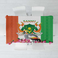 Green and orange kente-style tablecloth with crowned crane emblem and pink flower border