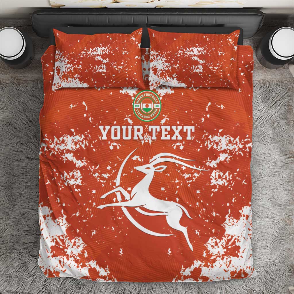 Orange graphic bedding set with two pillows and duvet; white splatter and 'YOURTEXT' print