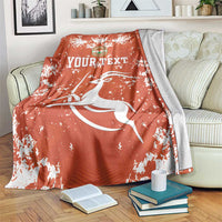 Orange football blanket with white splatter print and crest logo, draped on sofa