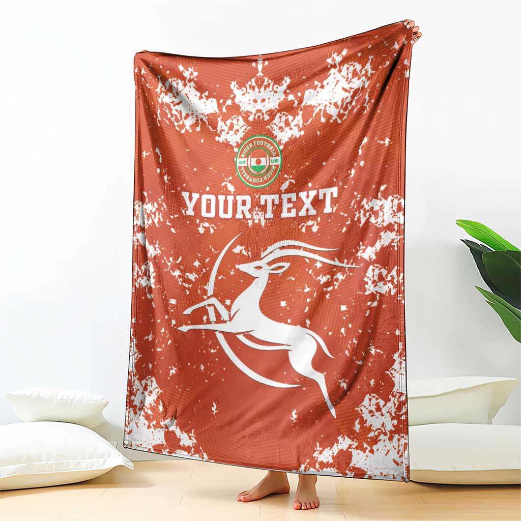 Orange football blanket with white splatter print, crest and “YOUR TEXT” across center