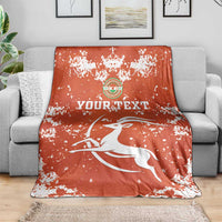 Orange football blanket with white splatter pattern, crest logo and leaping bird graphic