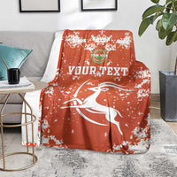 Orange football blanket with white splatter design, crest logo and leaping bird motif