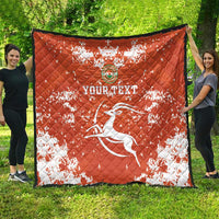 Orange quilt blanket draped outdoors with white splatter print, Niger crest, and soccer player graphic