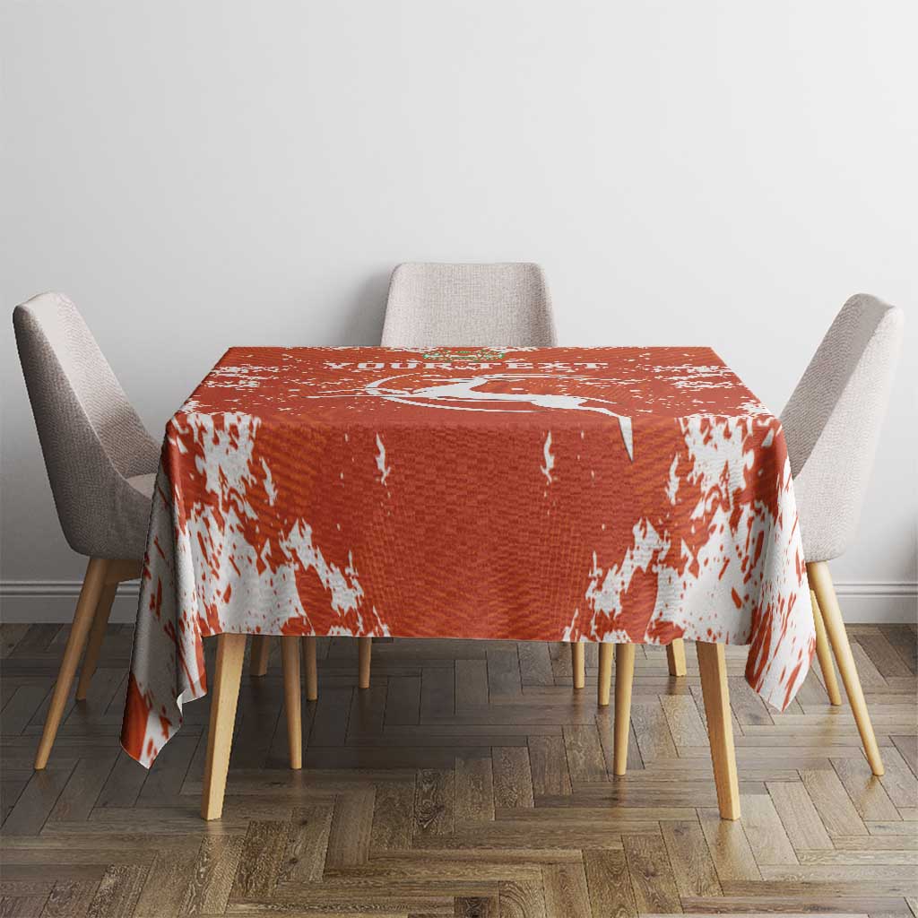 Orange football tablecloth with white splatter pattern on square dining table