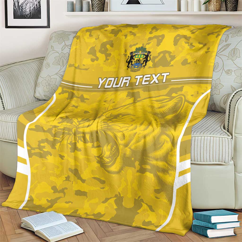 Custom yellow football blanket on sofa with crest, lion graphic, and 'YOUR TEXT' stripe