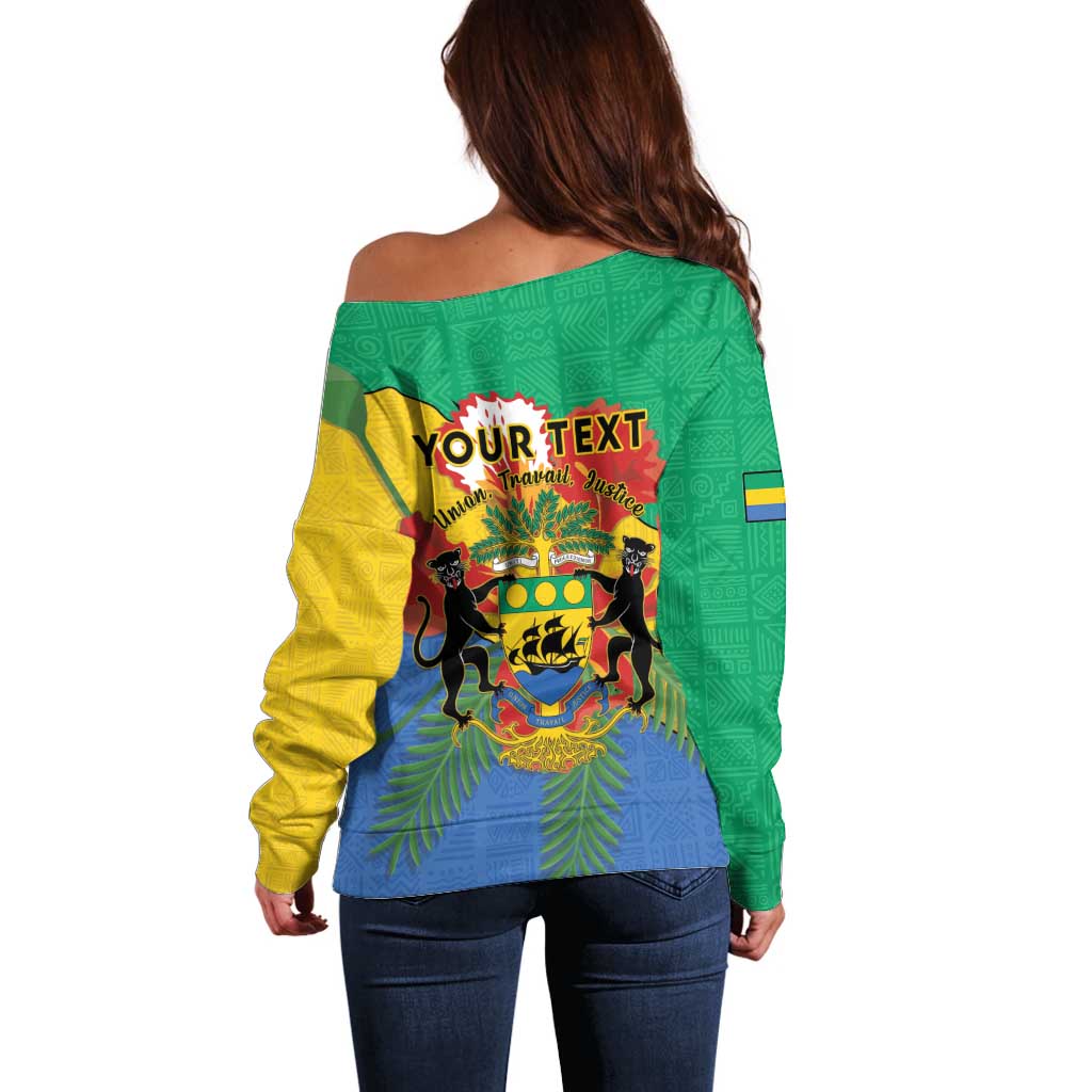 Green off-shoulder sweater coat with Gabon crest graphic on back and contrast sleeves
