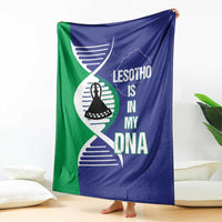 Lesotho DNA blanket with blue and green panels, emblem and map graphic, hanging on couch