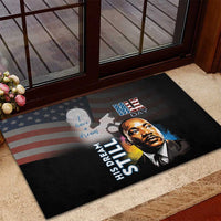 Black rubber doormat showing MLK portrait, “His Dream Still” lettering, and flag motif