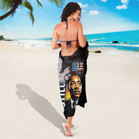Black beach sarong with MLK portrait centered and His Dream Still text, loose drape