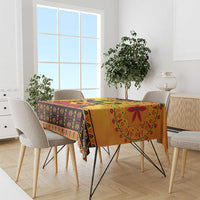 Orange Kwanzaa tablecloth with colorful African motif border draped over dining table.