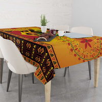 Orange Kwanzaa tablecloth with geometric stripe border and corner drape on dining table.
