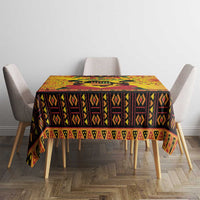 Orange Kwanzaa tablecloth with dark geometric center band and patterned hem on dining table.