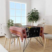 Black and red Christmas tablecloth with deer, houses, and geometric border on dining table