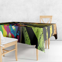Grunge-style tablecloth draped on wooden table, black and green with colorful abstract blocks