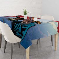Blue tablecloth with eagle hunter print and red trim on dining table, draped corner.