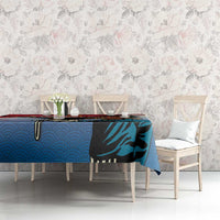 Blue tablecloth with eagle hunter graphic and red trim on dining table with chairs.