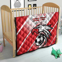 Red Tunisia football quilt on a crib with eagle mascot, soccer ball, and white diagonal stripes