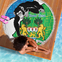 Round beach blanket, green-and-blue chimp coat of arms graphic, fringe border