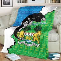 Green and blue Sierra Leone blanket with chimpanzees and coat of arms, spread on sofa