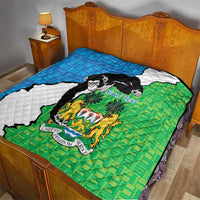 Sierra Leone quilt on bed featuring blue, white and green map with chimpanzee and coat of arms