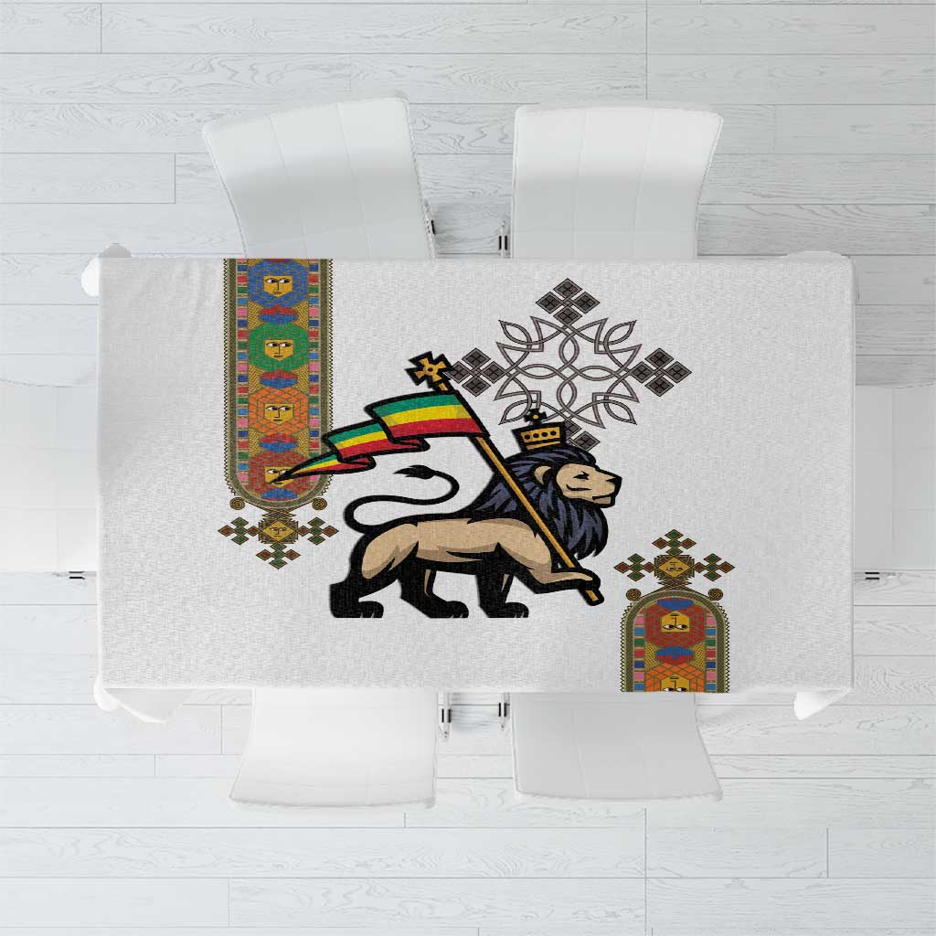 White tablecloth with central lion-of-Judah and cross medallion, colorful side border