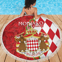 Round red and white Monaco crest beach blanket with fringed border on wooden deck