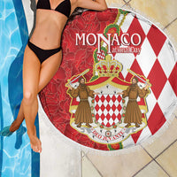 Round red and white Monaco crest beach blanket with fringed border, curved over poolside