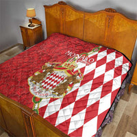 Red and white Monaco crest quilt blanket on bed, diamond pattern with coat of arms design.