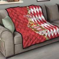 Red and white Monaco coat of arms quilt blanket on sofa, featuring diamond pattern side.