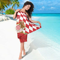 Red and white diamond-pattern sarong with crest emblem, wrapped and draped